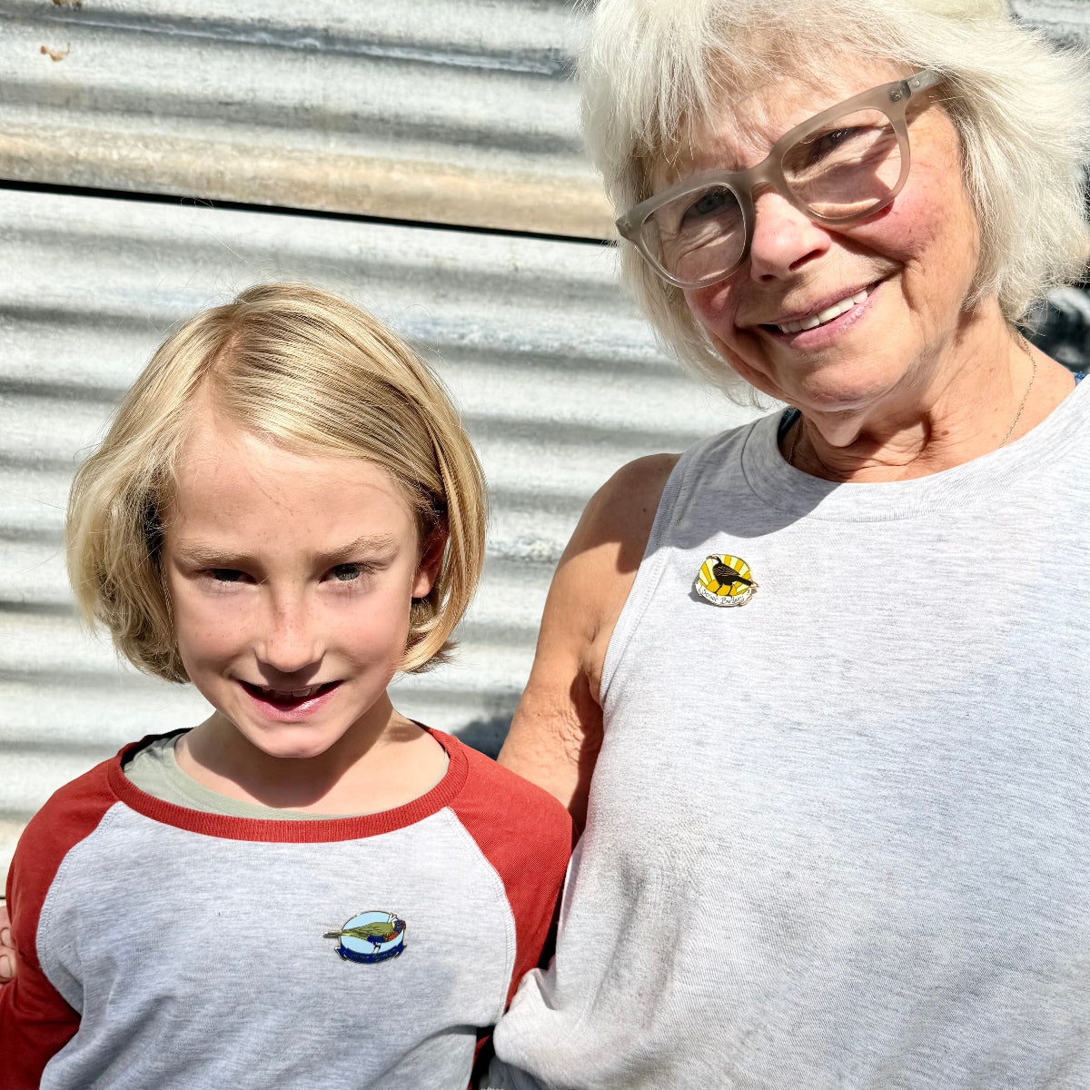 grandmother and her grandson standing together wearing matching enamel birder pins.