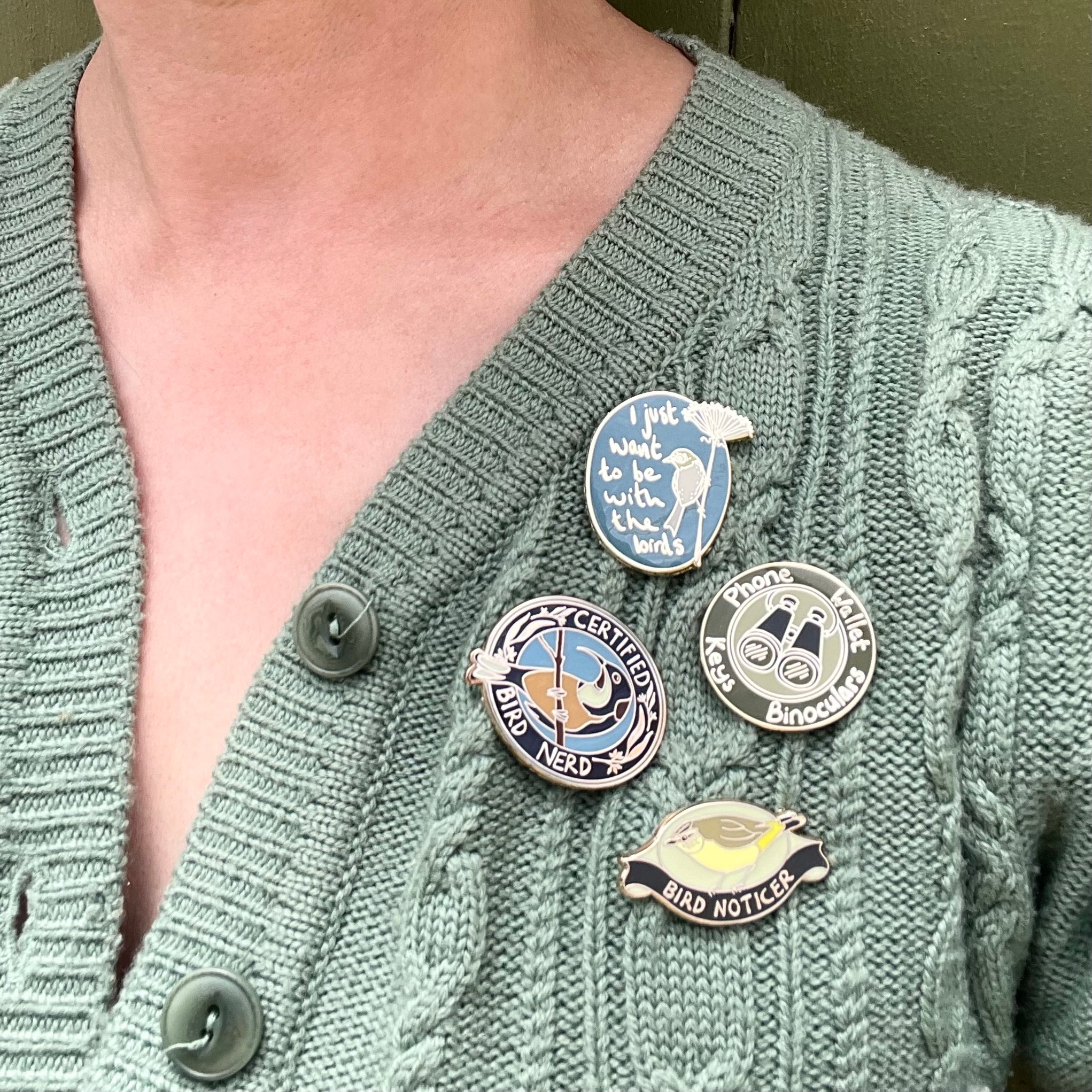 four birder pins on green cardigan