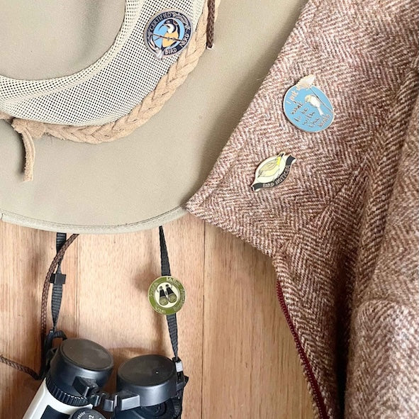 birder pins on hat coat and binoculars